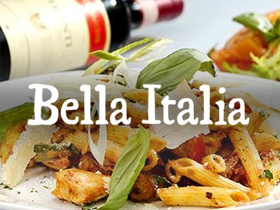 A chicken pasta meal with shavings of Parmesan and a bottle of wine lying on its side in the background 