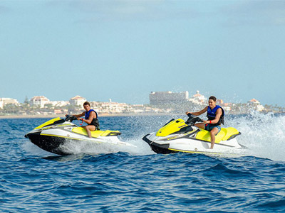 Two men on a Jet Ski, with another Jet Ski in the background