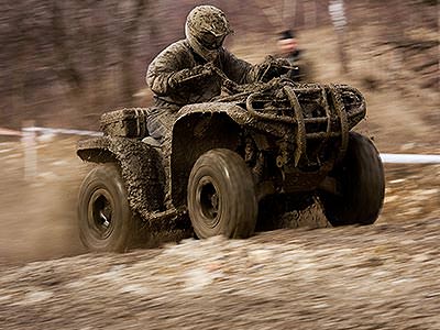 A man in camouflage quad biking on a dirt path