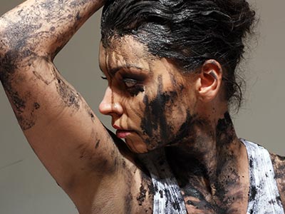 A woman covered in mud, with her arm in the air