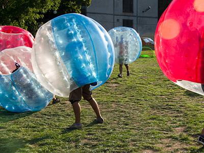 People playing on an outdoor pitch in inflatable zorbs