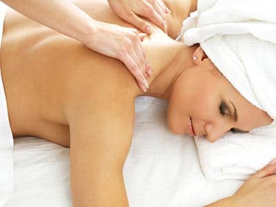 A woman receiving a back massage, with a towel on her head