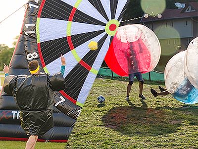 Ballseye & Bubble Football - A man kicking a ball at a giant target and a group of people playing bubble football