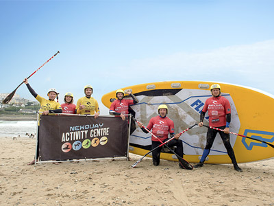A group of people posing in front of a SUP board in Newquay