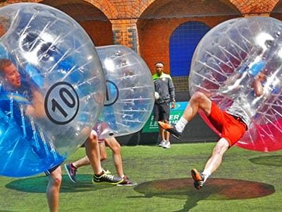 People playing in pink and blue zorbs on a pitch