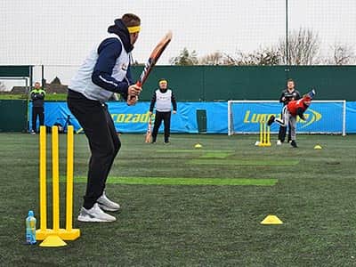 A man bowling a ball at a man holding a cricket bat 