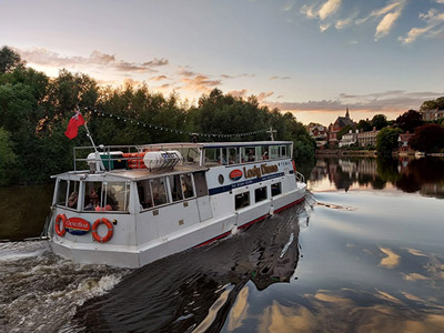 A white boat on a river bank at sunset