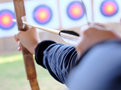 A man aiming with a bow and arrow during an outdoor archery session