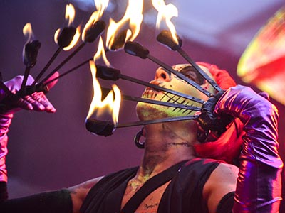 A person blowing on fire whilst juggling