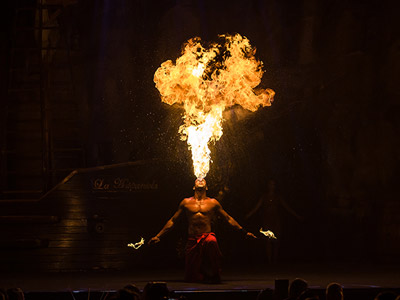 A man blowing fire from his mouth on stage at Pirates Reloaded - Quarter Deck in Magaluf
