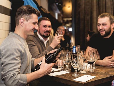 Three men in a bar, with lots of drinks on their table 