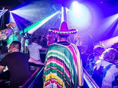 A man wearing a sombrero and Mexican outfit in a club