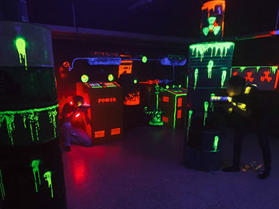 Two people holding laser guns in a dark room with multicoloured lights