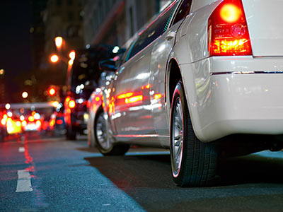 The back of a white limo on the street at night