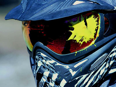 A close up of a person wearing a helmet with a paintball splat on the visor