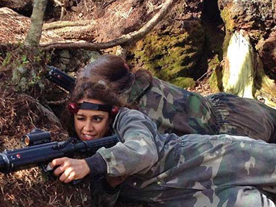 Two people crouching down in camouflage suits, with guns