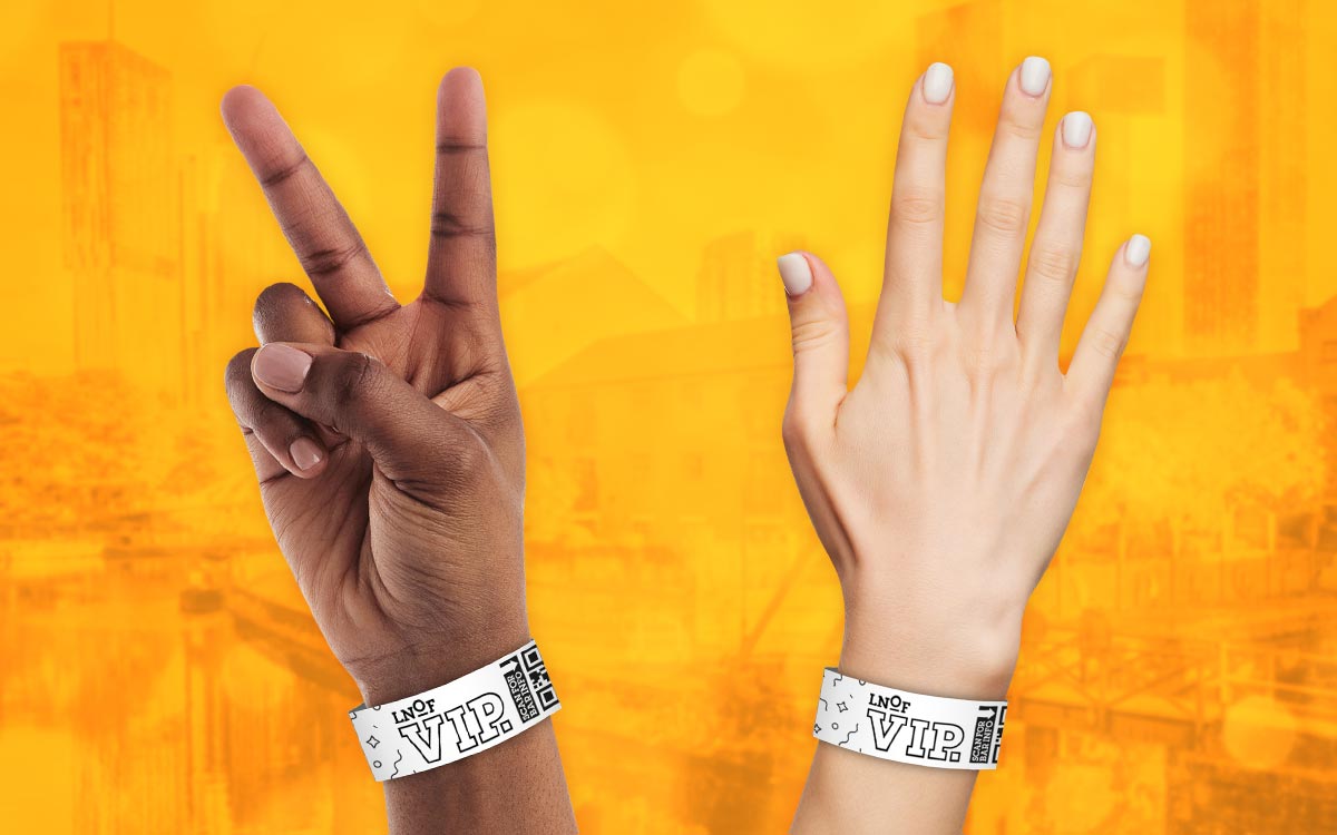 Two arms with wristbands on them that read LNOF VIP, in front of a yellow background. 