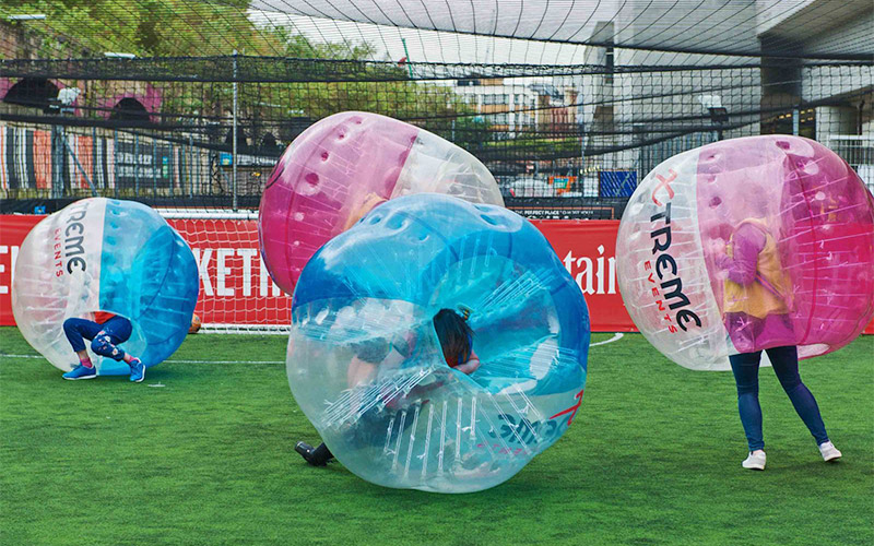 Four men in inflatable bubbles playing bubble football 