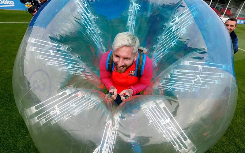 Lionel Messi smiling and posing in a blue inflatable bubble