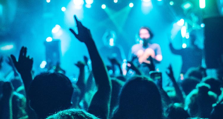A crowd watching a band in dim blue lighting. 