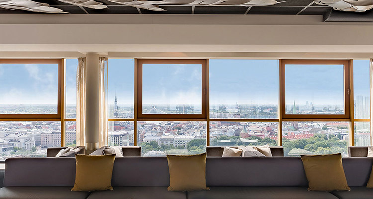 The Skyline Bar which has loads of grey sofa seating with a view over Riga in the daytime 
