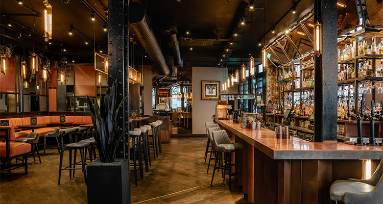 The bar at The Alchemist in Liverpool that is decked out in neutral colours and has booth seating 