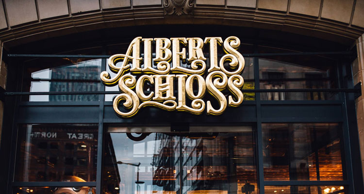 A venue with a fancy gold sign on it that reads Alberts Schloss. 
