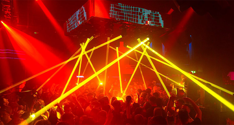 One of the rooms at Circuit York which has red and yellow club lighting, an LED display and loads of party goers 