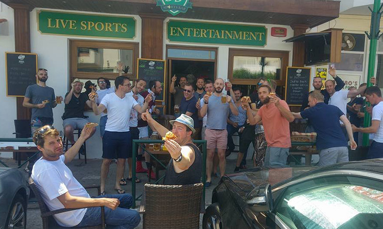 A group of people sat outside Sports Bar 33 drinking 