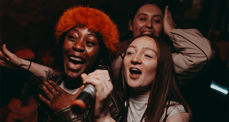 Three women singing into one microphone at Let's Sing Karaoke Bar