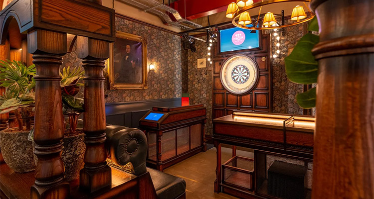A room at Flight Club in Cardiff that has a dart board and dark wooden panelling giving it a grand appearance 