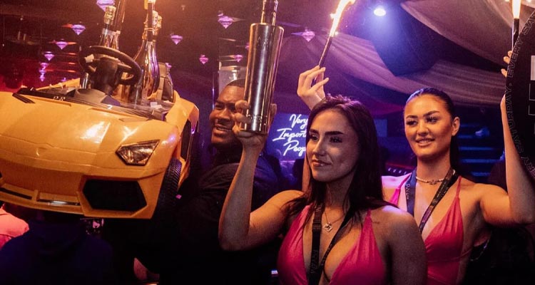 A yellow car hanging from the ceiling and two women holding sparklers. 
