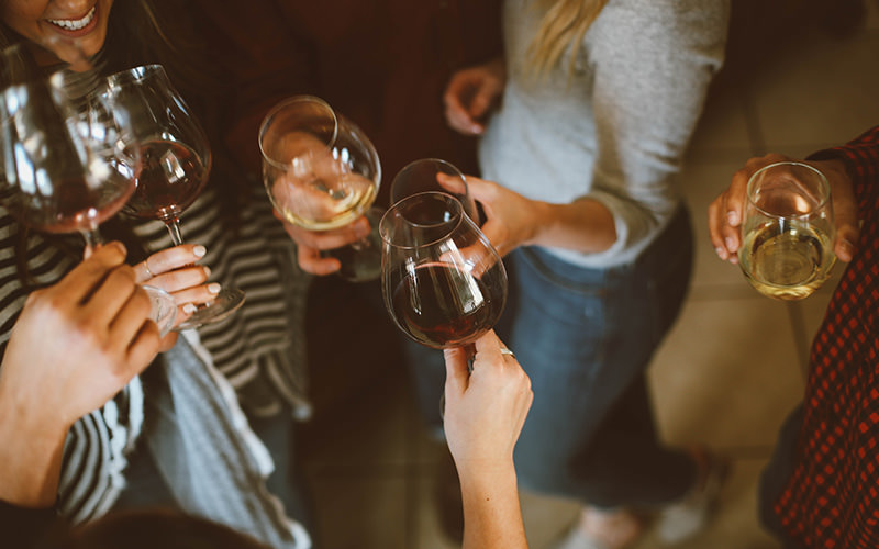 Some girls holding wine glasses together in a kitchen