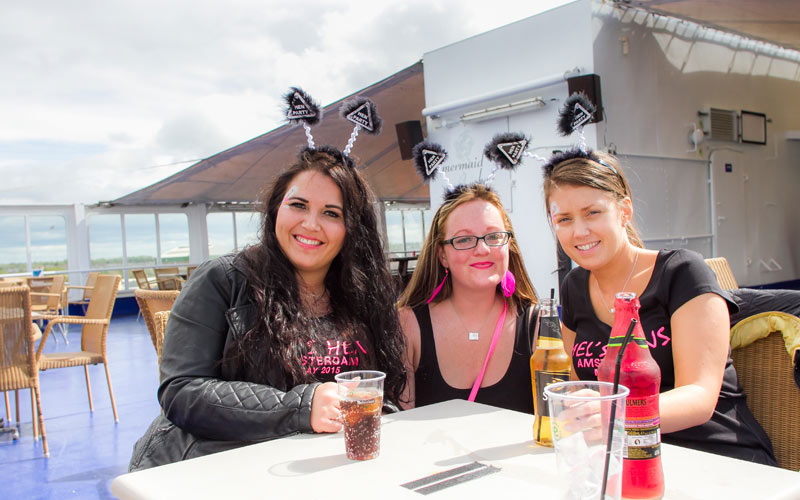 Three girls drinking, on a boat