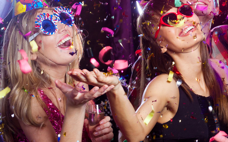 Some girls wearing sunglasses in a club, with confetti pouring down from the ceiling