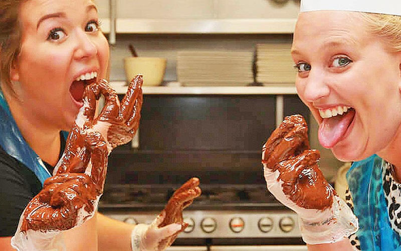 Some women with chocolate on their gloves after a chocolate making class