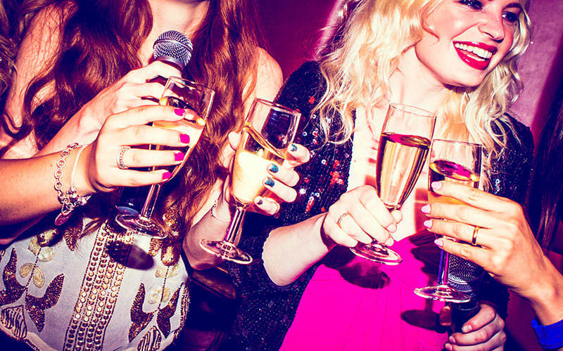 Two girls holding microphones and glasses of Prosecco