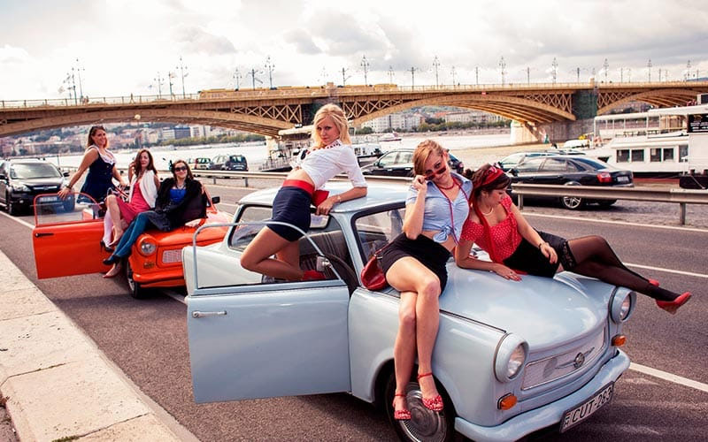Two Mini cars with girls lying on top of them