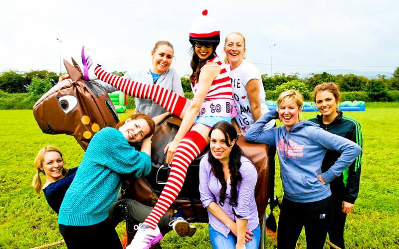 Some girls in fancy dress, riding a fake horse
