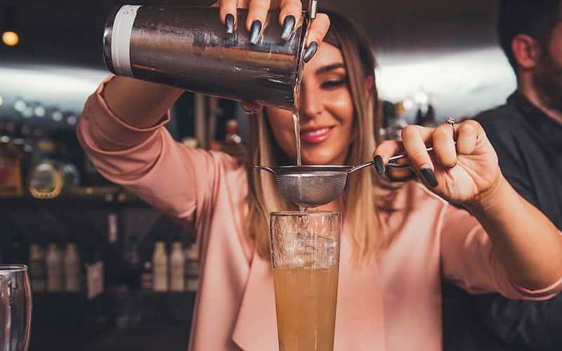 A girl pouring a drink into a glass