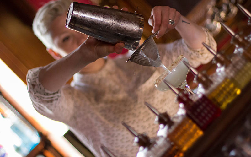 A woman pouring a cocktail through a sieve
