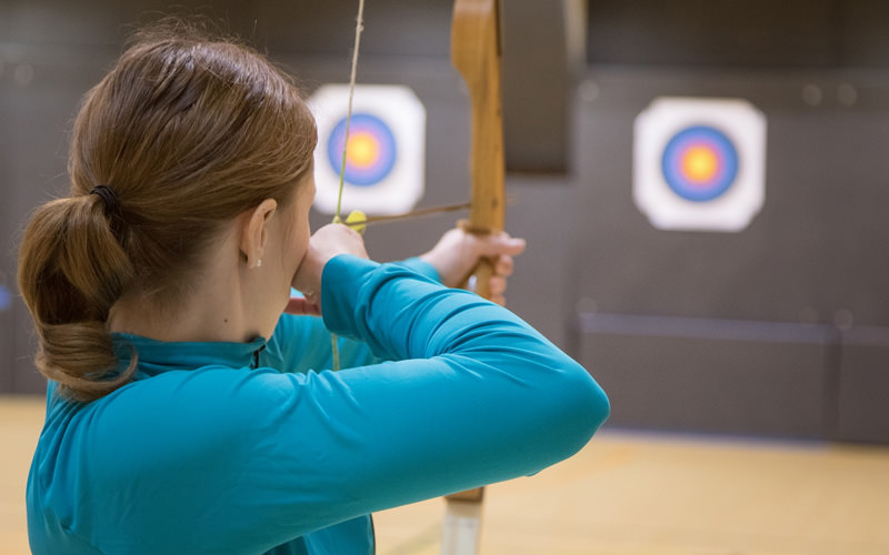 A girl aiming an arrow at a target board