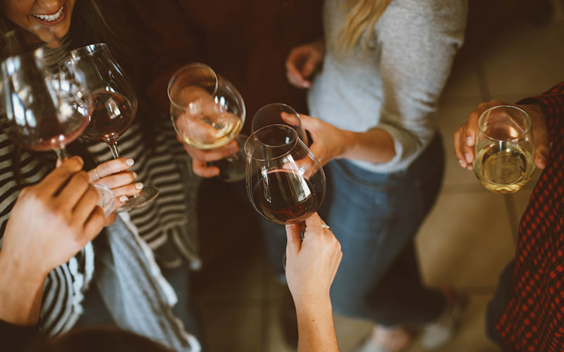 Some girls holding their wine glasses out in front of them