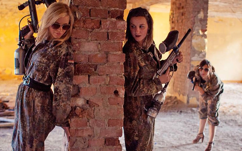 Three girls wearing army overalls, with paintball guns