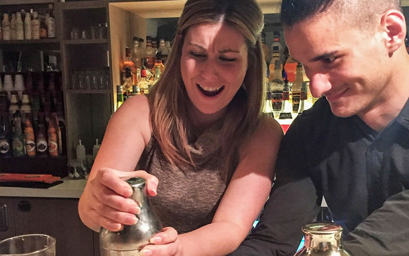 A woman receiving a cocktail making class from an instructor