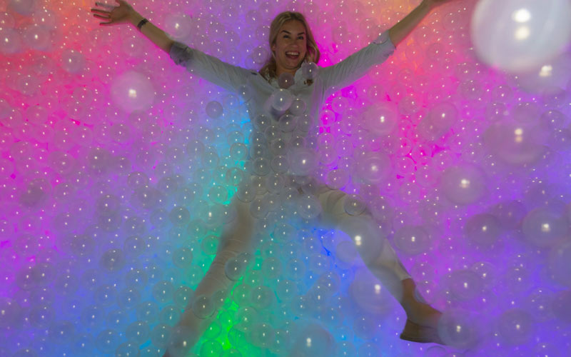 A woman lying in a ball pool in a London club