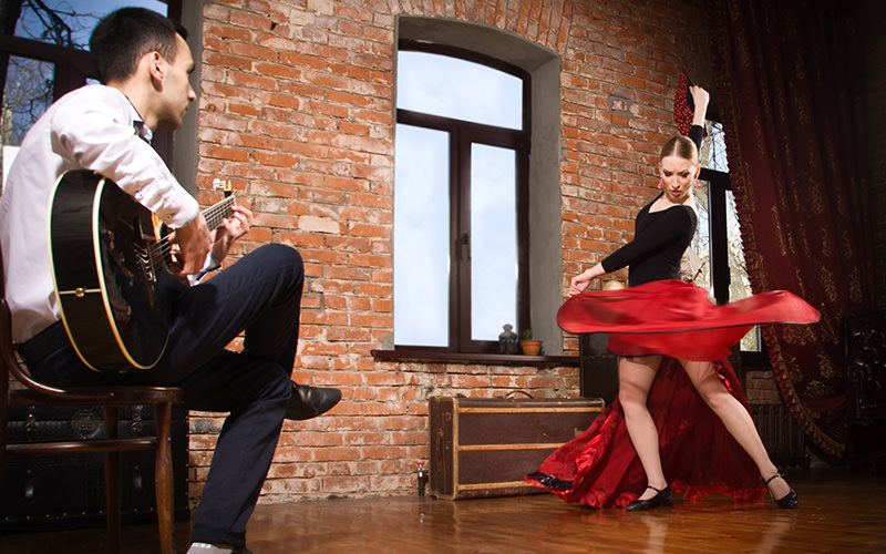 A woman flamenco dancing whilst a man plays the guitar