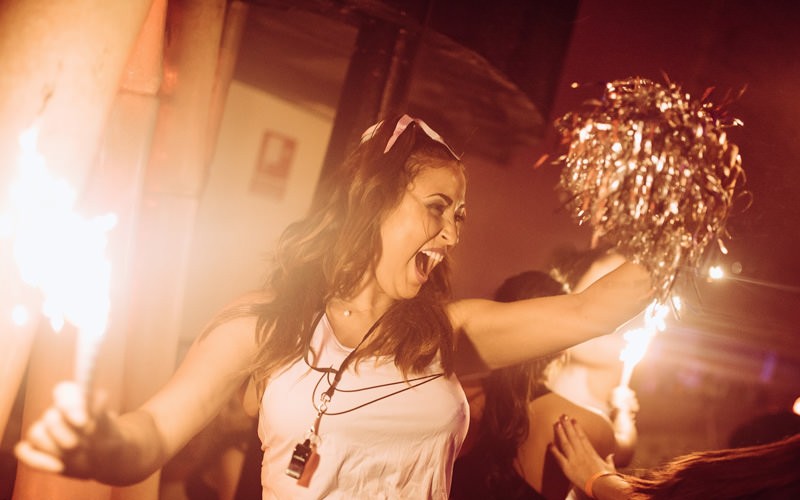 A girl holding a sparkly pom pom with a whistle around her neck
