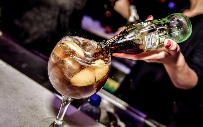 A hand pouring a coke into a bottle