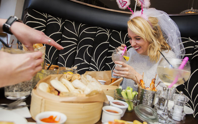 A hen with a veil on, sucking from a willy straw